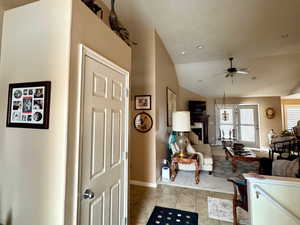 Interior space with a textured ceiling, lofted ceiling, ceiling fan, and light tile patterned floors