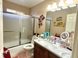 Full bathroom featuring tile patterned flooring, toilet, a textured ceiling, enclosed tub / shower combo, and vanity