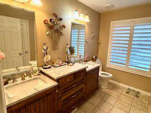 Bathroom with a textured ceiling, vanity, and toilet