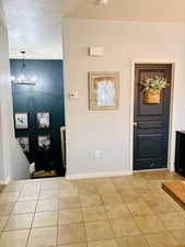 Tiled entrance foyer featuring an inviting chandelier and baseboards