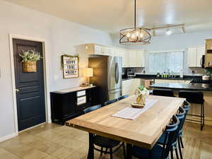 Kitchen with a notable chandelier, a sink, appliances with stainless steel finishes, dark countertops, and pendant lighting