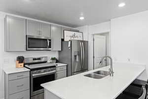 Kitchen with gray cabinets, sink, stainless steel appliances, and kitchen peninsula