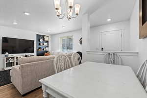 Dining area featuring hardwood / wood-style flooring, an inviting chandelier, and a textured ceiling