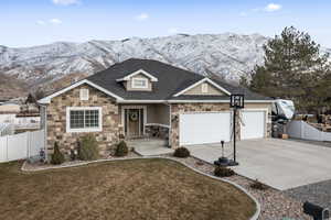 View of front of house with a mountain view, a front yard, and a garage