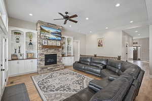 Living room with light hardwood / wood-style flooring, ceiling fan, and a fireplace