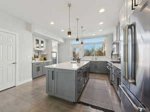 Kitchen with white cabinetry, high quality appliances, gray cabinets, and a center island