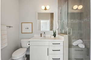 Ensuite bathroom with vanity, a shower with shower door, and toilet