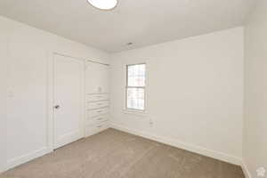 Unfurnished bedroom featuring a textured ceiling and light carpet