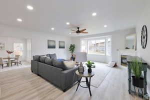 Living room featuring ceiling fan, light wood-type flooring, and a healthy amount of sunlight