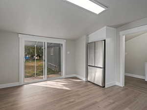 Unfurnished room featuring light wood-type flooring and lofted ceiling