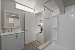 Bathroom with hardwood / wood-style flooring, bathing tub / shower combination, and vanity