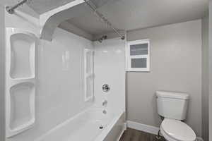 Bathroom featuring hardwood / wood-style floors, toilet, and washtub / shower combination