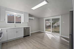 Kitchen featuring sink, stainless steel appliances, white cabinetry, and a wall unit AC