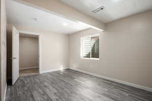 Unfurnished room with a textured ceiling and dark hardwood / wood-style floors