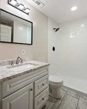 Bathroom with vanity, tiled shower, and toilet