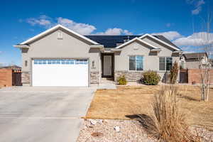 View of front facade featuring solar panels and a garage