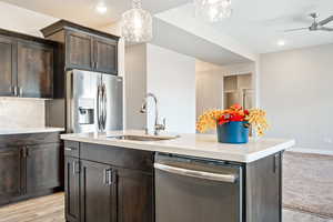 Kitchen featuring dark brown cabinets, sink, stainless steel appliances, and an island with sink