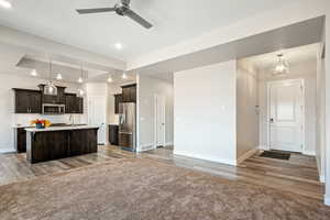 Kitchen with a center island with sink, appliances with stainless steel finishes, backsplash, pendant lighting, and dark brown cabinetry