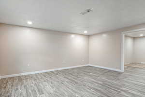 Basement with light hardwood / wood-style floors and a textured ceiling