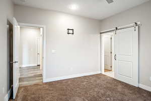 Unfurnished bedroom featuring light colored carpet and a barn door