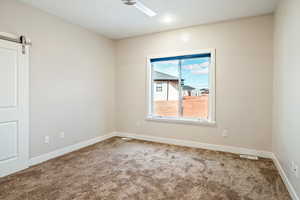 Unfurnished room featuring a barn door and carpet floors