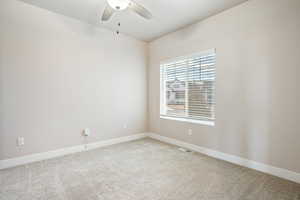 Empty room featuring ceiling fan and carpet flooring