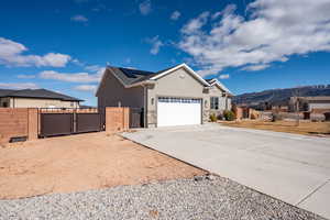 View of front facade featuring a mountain view, a garage, and solar panels