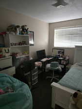 Unit 2 Bedroom featuring dark colored carpet and a textured ceiling