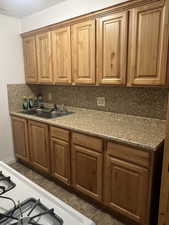 Unit 1 Kitchen with dark tile patterned floors, sink, range, and decorative backsplash