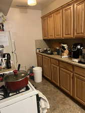 Unit 1 Kitchen with a textured ceiling, white gas stove, and backsplash