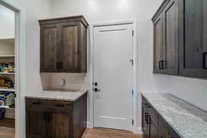 Interior space featuring light stone countertops, dark brown cabinetry, and light hardwood / wood-style flooring