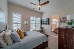 Carpeted bedroom with ceiling fan and ensuite bath