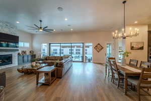 Living room with a fireplace, hardwood / wood-style floors, and ceiling fan with notable chandelier