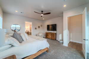 Carpeted bedroom featuring ceiling fan and ensuite bath