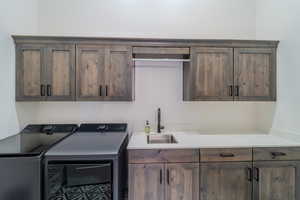 Clothes washing area with sink, cabinets, and independent washer and dryer