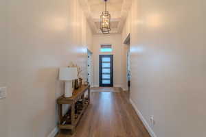 Doorway with wood-type flooring, a notable chandelier, and a towering ceiling