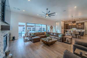 Living room featuring a fireplace, light hardwood / wood-style flooring, and ceiling fan with notable chandelier