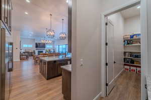 Kitchen featuring sink, light stone counters, light wood-type flooring, pendant lighting, and high end refrigerator