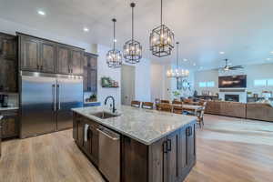 Kitchen with an island with sink, appliances with stainless steel finishes, sink, and dark brown cabinets