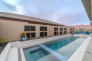 View of swimming pool featuring an in ground hot tub, a mountain view, and a patio