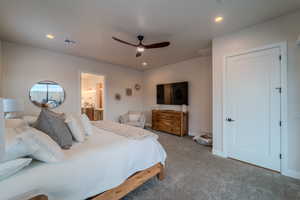 Bedroom featuring ensuite bathroom, carpet, and ceiling fan