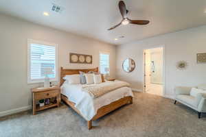 Bedroom with light carpet, ensuite bathroom, and ceiling fan