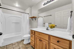 Full bathroom featuring vanity, toilet, and shower / bathtub combination with curtain