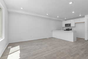 Kitchen featuring stainless steel appliances, white cabinets, light hardwood / wood-style floors, sink, and kitchen peninsula