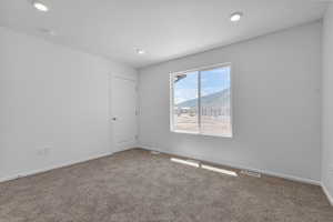 Empty room with a mountain view, carpet flooring, and a textured ceiling