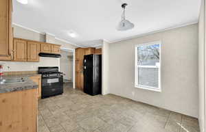 Kitchen featuring sink, hanging light fixtures, crown molding, and black appliances