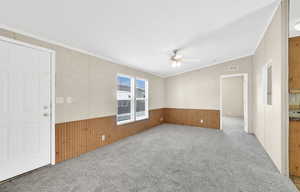 Empty room featuring ceiling fan, ornamental molding, and light colored carpet