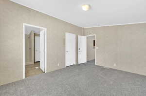 Unfurnished bedroom with carpet floors, ornamental molding, and ensuite bathroom