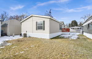 View of property exterior featuring cooling unit, a yard, and a storage unit