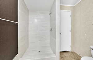 Bathroom featuring ornamental molding, a tile shower, and toilet